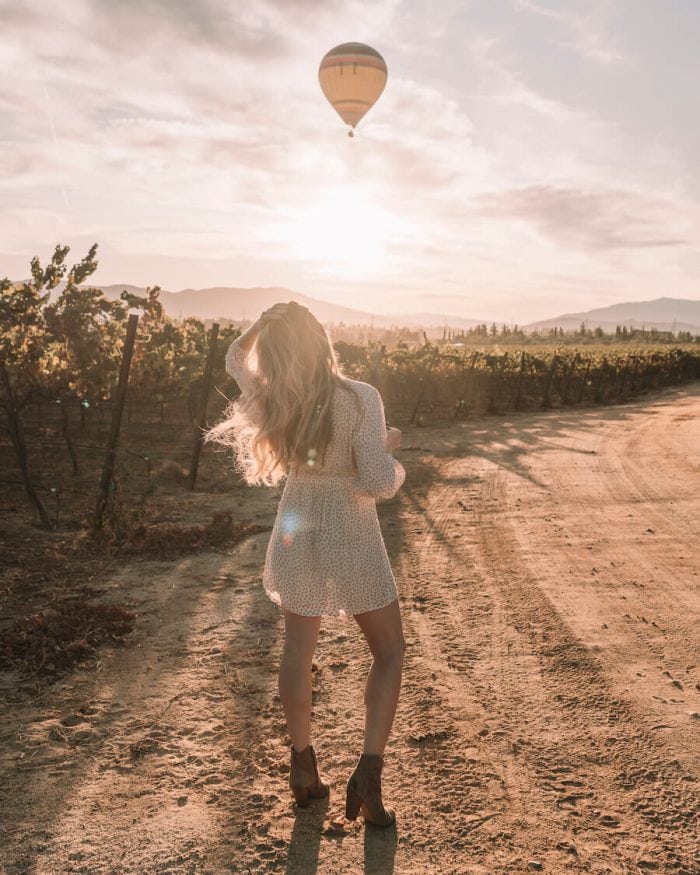 Michelle Halpern walking at Carter Estate Winery with hot air balloon flying overhead